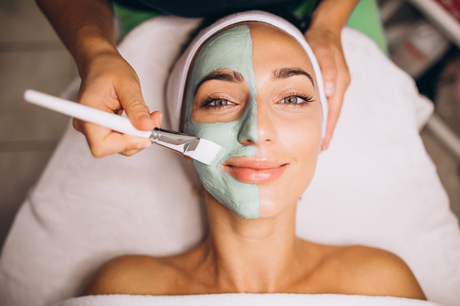 Cosmetologist applying mask on a face of client in a beauty salon